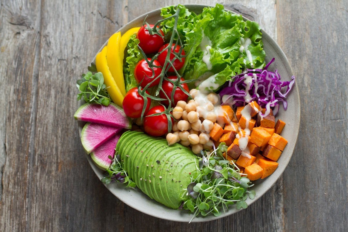 An overhead view of a colorful salad with avocado, greens, and chickpeas