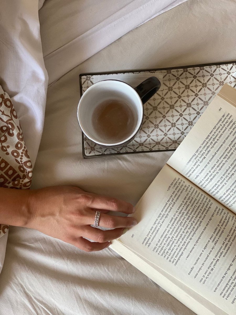 A calm bedside scene with an open book and a warm drink