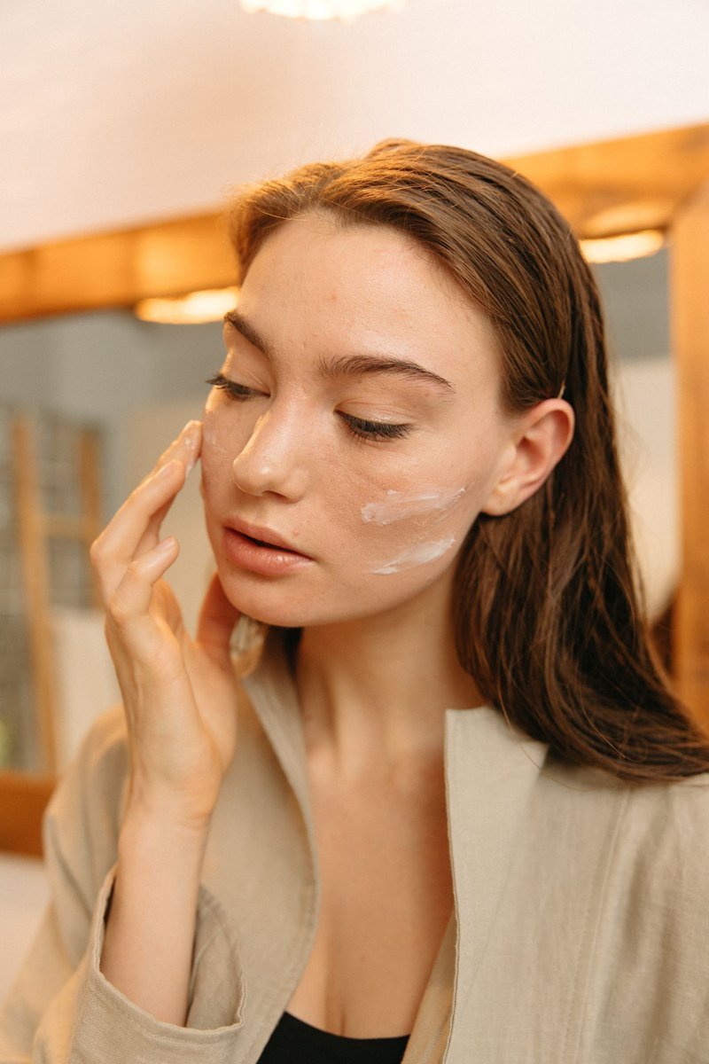 A woman gently applying a facial moisturizer